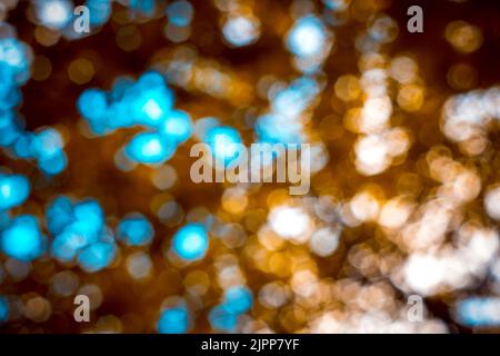 Absichtlich unscharf kreisförmige, ausgelasteten und dichten Unschärfen mit Bokeh-Kugeln. Abstrakte Aufnahme in Blau-, Gelb-, Braun- und Orange-Tönen. Stockfoto