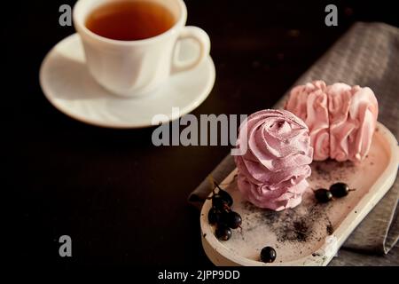 Ästhetisches Dessert - Beerenmarmelibe mit Johannisbeere und einer Tasse schwarzem Tee. Herbstlich gemütliche, stimmungsvolle Vorspeise. Gesunde Süßigkeiten, natürliche Lebensmittel Zucker und glutenfrei. Speicherplatz kopieren. Stockfoto