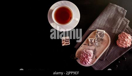 Ästhetisches gemütliches Hausfrühstück. Tasse schwarzen Tee und rosa Marshallows mit Johannisbeere. Gesunde Süßigkeiten, Zucker und glutenfreie natürliche Dessert . Speisen von oben mit Kopierplatz. Extra breites Banner. Stockfoto