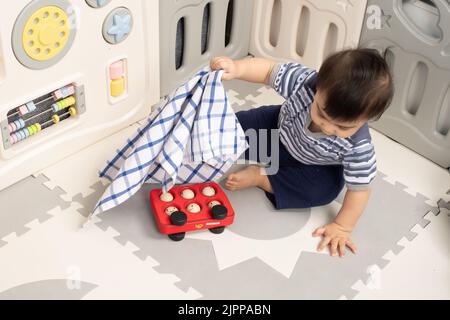 11 Monate alt Baby Junge zu Hause Hebetuch zu finden versteckte Spielzeug Piaget Objekt Dauerhaftigkeit Serie #2 Stockfoto