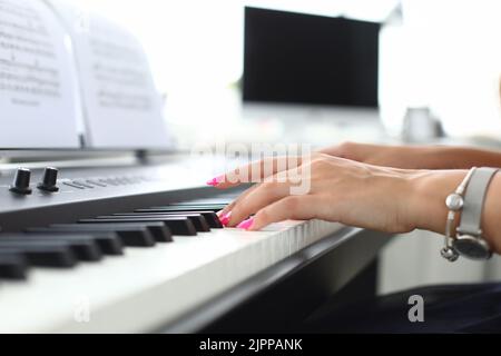 Weibliche Hand drückt die Tasten des Synthesizers und lernt zu spielen Stockfoto