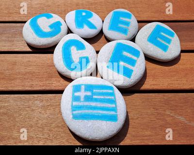 Griechenland Ländername auf den Steinen auf Holzdiele Hintergrund gemalt. Inskription auf dem Meer Steine. Stockfoto