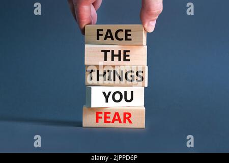 Stellen Sie sich den Dingen, die Sie fürchten Symbol. Auf Holzblöcken auf einem schönen grauen Hintergrund stehen Begriffe vor den Dingen, die Sie fürchten. Geschäftsmann Hand. Unternehmen und Stockfoto