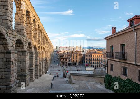 Blick auf die Stadt Segovia im Schatten des römischen Aquädukts und die verschneiten Berge im Hintergrund Stockfoto