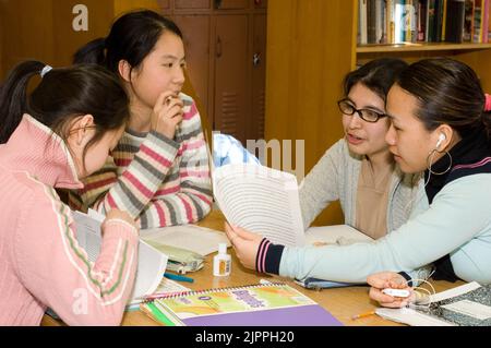 Öffentliche Schule High School Gruppe von Schülerinnen diskutieren ein Papier, sitzen am Tisch im Klassenzimmer Stockfoto