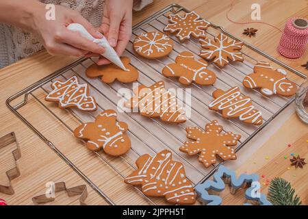 Frauenhänden schmücken hausgemachte Weihnachts Lebkuchen, Draufsicht Stockfoto