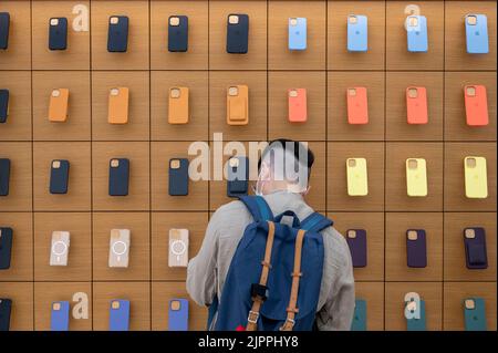 Hongkong, China. 19. August 2022. Ein Shopper blickt auf eine Wand, die voll mit iPhone-Hüllen besetzt ist, im amerikanischen multinationalen Technologiekonzern Apple Store in Hongkong. (Bild: © Budrul Chukrut/SOPA Images via ZUMA Press Wire) Stockfoto