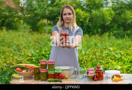 Eine Frau konserviert Gemüse in Gläsern. Selektiver Fokus. Essen. Stockfoto