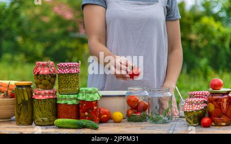 Eine Frau konserviert Gemüse in Gläsern. Selektiver Fokus. Essen. Stockfoto