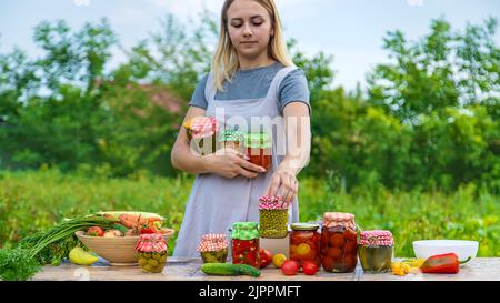 Eine Frau konserviert Gemüse in Gläsern. Selektiver Fokus. Essen. Stockfoto