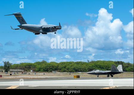 Eine US Air Force C-17 Globemaster III hebt am 12. August 2022 als F-22 Raptor der US Air Force während der Kaneohe Bay Air Show auf der Marine Corps Base Hawaii ab. Beide Flugzeuge sind der Joint Base Pearl Harbor-Hickam zugeordnet und werden von Mitgliedern der Hawaii Air National Guard betrieben. Die Veranstaltung wurde abgehalten, um die langjährigen Beziehungen des Militärs zur lokalen Gemeinschaft zu feiern und der Öffentlichkeit die Gelegenheit zu geben, die Fähigkeiten der gemeinsamen Truppe zu erleben. (USA Foto der Air National Guard von Staff Sgt. John Linzmeier) Stockfoto