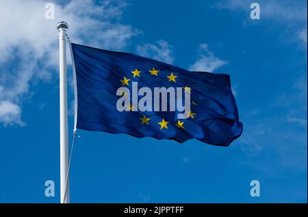 Flagge der EU auf blauem Himmel Hintergrund. Flagge der Europäischen Union winkt im Wind. Stockfoto