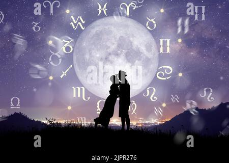 Astrologische Sternzeichen innerhalb des Horoskopkreises. Pärchen singen und tanzen über dem Tierkreis Rad und Milchstraße Hintergrund. Stockfoto