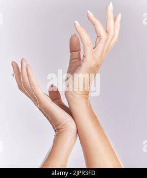 Weiche, Maniküre Hände oder Schönheitsbehandlung Nahaufnahme von weiblichen Modell Handflächen berühren in eleganter Hand Pose isoliert auf lila Studio Hintergrund. Hautpflege Stockfoto