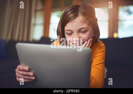 Wow, ich habe das nie hingestellt. Ein entzückendes kleines Mädchen, das zu Hause ein digitales Tablet auf dem Boden benutzt. Stockfoto