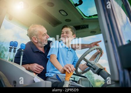 Blick auf die Straße. Ein Bauer und sein Sohn im Cockpit eines modernen Traktors. Stockfoto