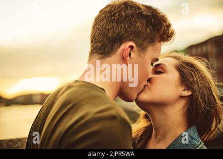 Liebe von ganzem Herzen. Ein liebevolles junges Paar, das einen Kuss teilt, während es auf einem Date ist. Stockfoto