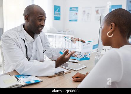 Ein Arzt, der einer Frau in seinem Büro Informationen über das Krankenhaus eines Patienten in einer Klinik gibt und medizinische Vorteile erklärt. Afroamerikanischer Hausarzt oder Gesundheitswesen Stockfoto