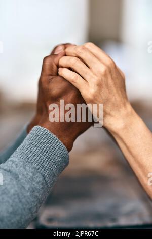 Zwei Herzen, die als eins schlagen. Zwei unkenntliche Menschen halten sich die Hände. Stockfoto