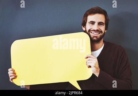Holen Sie sich Ihre Gedanken heraus, damit jeder sie sehen kann. Studioporträt eines jungen Mannes, der eine Sprechblase vor einem grauen Hintergrund hält. Stockfoto