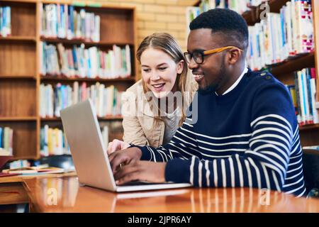 Nun, erhalten Sie volle Noten mit all diesen Informationen. Eine junge Frau schaut auf, während ein männlicher Student auf einem Laptop arbeitet. Stockfoto
