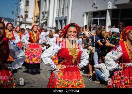 Frauen werden bei der Parade in traditionellen roten Kostümen gesehen. Mehr als eineinhalb tausend Frauen, die sich akribisch gekleidet haben, um die Geschichte der Wiener Frauen darzustellen, Stolz zogen sie entlang der Straßen der Stadt, um die schönen traditionellen Kostüme während der Mordomia Parade zu zeigen, die Teil der Romaria d'Agonia ist, die wegen der COVID-19 Pandemie zwei Jahre lang in der Warteschleife war. Tragen Sie die schönen Folklore-Kostüme aus den verschiedenen Dörfern, die Teil der Viana do Castelo Gegend sind, mit großen Mengen von Gold um den Hals, viele Gegenstände tatsächlich Erbstücke aus Jahrhunderten, diese Mordom Stockfoto