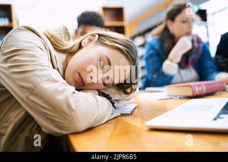 Eine Pause ist genauso wichtig: Ein Student, der in der Bibliothek einschläft. Stockfoto