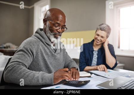 Es sieht so aus, als hätten wir noch etwas mehr übrig. Ein älteres Paar, das zu Hause an seinen Finanzen arbeitet. Stockfoto