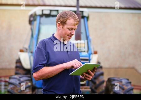 Der smarte Bauer. Ein Landwirt, der auf seinem Bauernhof ein digitales Tablet verwendet. Stockfoto