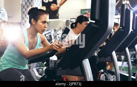 Eine Gruppe junger Menschen, die im Fitnessstudio an elliptischen Geräten trainieren. Stockfoto