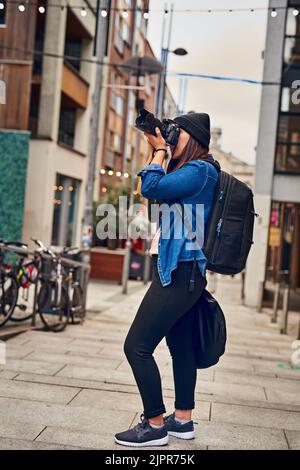 Die Welt durch meine Kamera betrachten. Eine Frau, die draußen mit ihrer Kamera fotografiert. Stockfoto