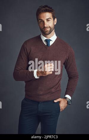 Power Poses. Studioporträt eines stilvoll gekleideten jungen Mannes, der vor grauem Hintergrund posiert. Stockfoto