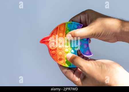 Drücken Sie ein buntes Anti-Stress-Sinnesspielzeug Fidget Push Pop it Spiel in den Händen halten Stockfoto