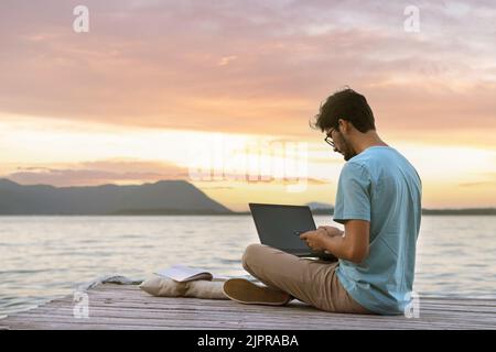 Junger, freier, digitaler Nomade, der an einem tropischen Strand unterwegs und arbeitet. Fernarbeit und Nomadismus Stockfoto