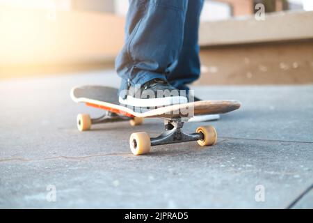 Beschnittene Ansicht eines jungen Mannes, der auf einem Skatepark mit schwarzen Sneakers auf dem Skateboard skaten - Extremsport, Freundschaft, Jugendkonzept - Selective Focus Stockfoto