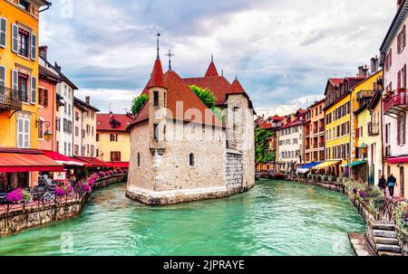 In der Nähe des Kanals Thiou in der Altstadt von Annecy in Frankreich spazieren die Menschen um den mittelalterlichen Palast Palais de l'Isle - Travel Concept Stockfoto