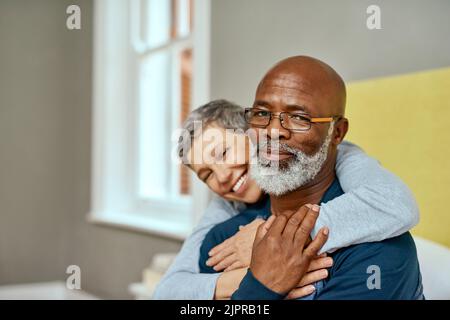 Nach all den Jahren lassen Sie mich immer noch lächeln. Ein älteres Ehepaar umarmt sich zu Hause. Stockfoto