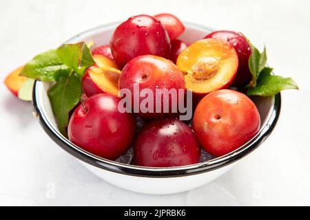 Pflaumen in weißem Teller auf weißem Hintergrund. Draufsicht. Stockfoto