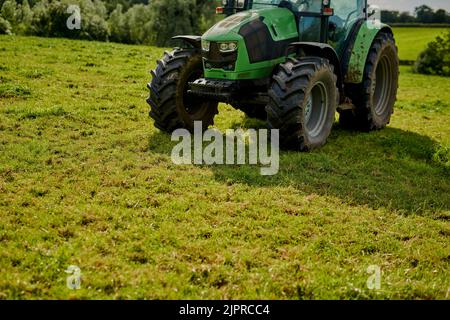 Kein Bauernhof ist komplett ohne Traktor. Aufnahme eines grünen Traktors auf einem offenen Stück Ackerland in einem hohen Winkel. Stockfoto