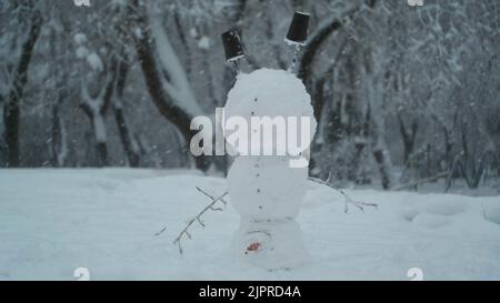 Fröhlicher lustiger Schneemann akrobatin auf dem Kopf, vor dem Hintergrund eines starken Schneefalls. Schneemann steht auf seinem Kopf. Odessa, Ukraine Stockfoto