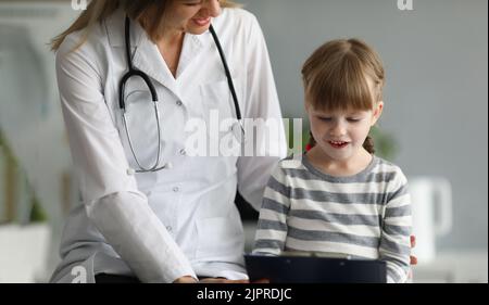 Kleine schöne Mädchen kommuniziert mit weiblichen Arzt in der Klinik Stockfoto