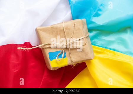 Auf den Flaggen Polens und der Ukraine, der humanitären Hilfe und der Unterstützung der Ukraine, dem Porto und der Post liegt ein Papierkarton mit einer bemalten Flagge der Ukraine Stockfoto