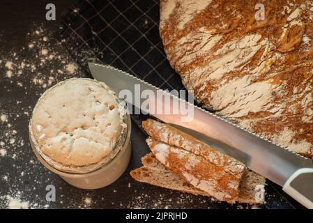 Brot aus handwerklichem Weizen und Roggenbrot mit graham-Mehl. Sauerteig-Starter auf dunklem Hintergrund. Draufsicht. Stockfoto