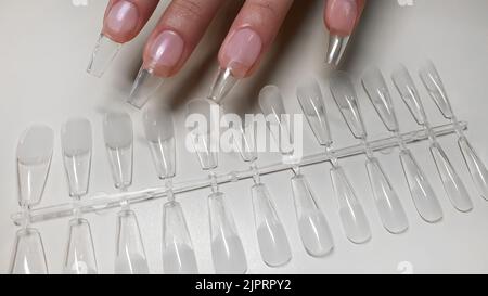 Schritt-für-Schritt-Anleitung zur Nagelverlängerung auf Gelspitzen. Maniküre, Hände im Vordergrund. Kopierraum Stockfoto