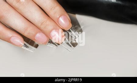 Schritt-für-Schritt-Anleitung zur Nagelverlängerung auf Gelspitzen. Maniküre, Hände im Vordergrund. Kopierraum Stockfoto