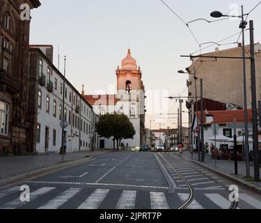 Igrega do Carmo (Carmo-Kirche) nähert sich dem Sonnenuntergang, einer katholischen Kirche in Porto, Portugal. Straßenmarkierung und Fußgängerüberweg vor dem Hotel. Stockfoto