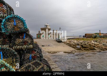 Blacksod, Irland - 19. Juli 2022: Blick auf den Hafen und den Leuchtturm von Blacksod mit vielen Krabbenfallen und Hummertöpfen auf den Docks Stockfoto