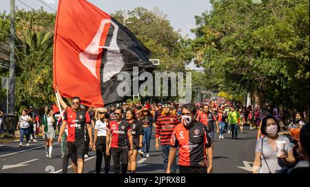 Die Gruppe von Fußballclubfans bei der Atlas-Meisterschaftsparade, die mit einer großen Flagge auf der Straße läuft Stockfoto