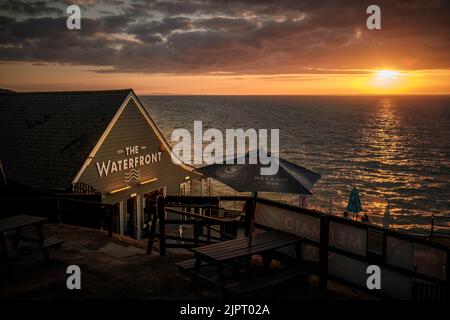 August 2022, Isle of Wight, Großbritannien. Sonnenuntergang in Totland Bay mit dem Café und Restaurant am Wasser, mit Blick auf den Solent mit einem wunderschönen Stockfoto