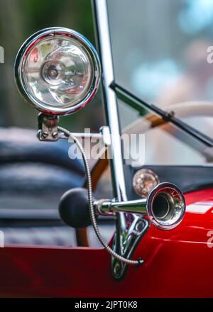 Glänzendes Stahlhorn auf rotem Oldtimer, Nahaufnahme Detail, nur Metallfelge im Fokus Stockfoto